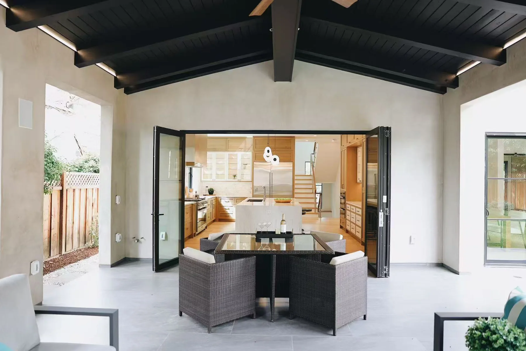 Outdoor entertaining area with dining table and open folding doors to the kitchen