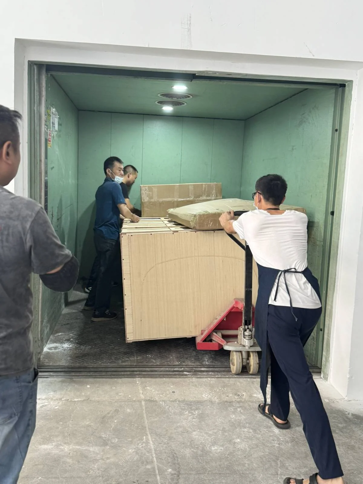 Packed furniture moved through freight elevator during delivery preparation