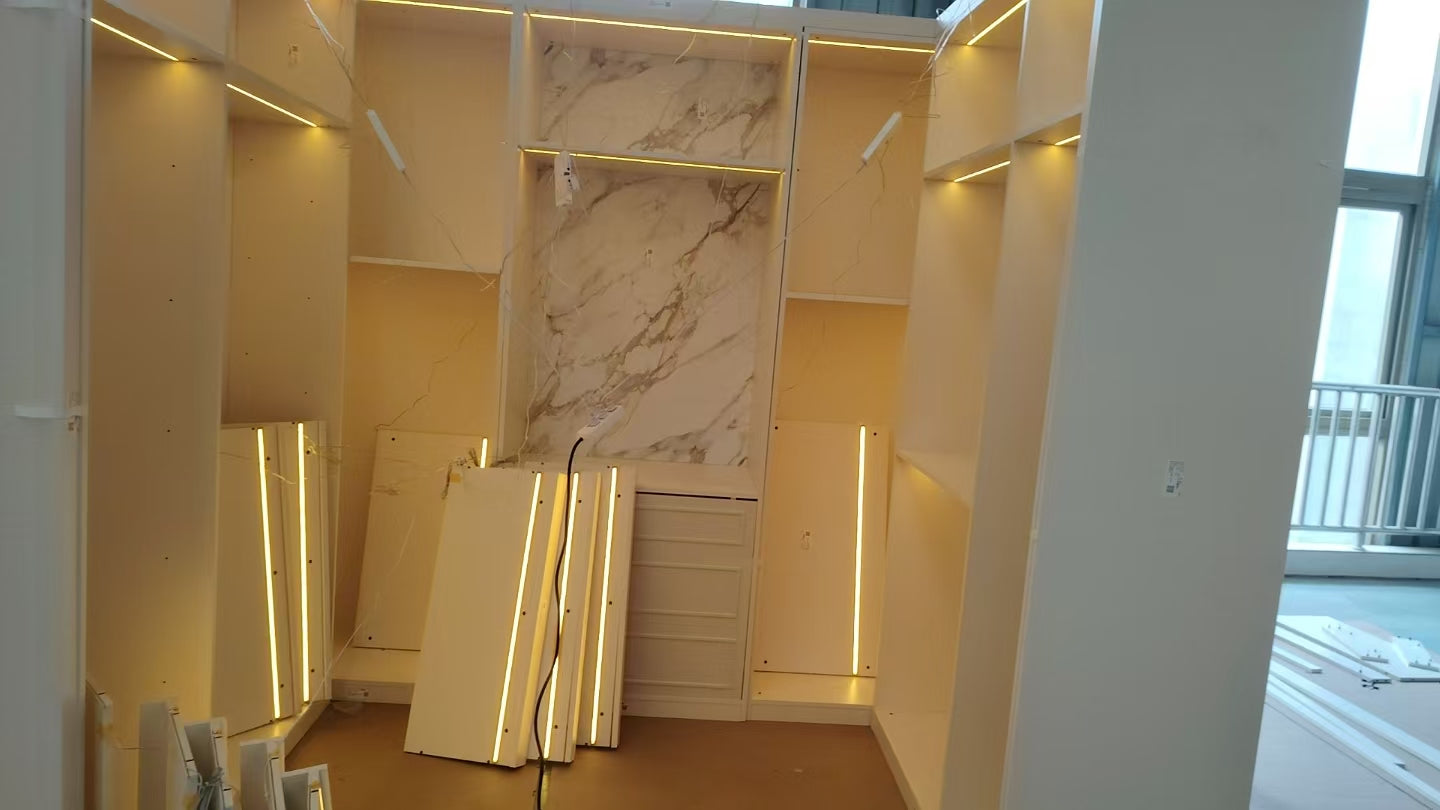 Cabinetry during installation with LED channels lit and the stone-grain back panel in place