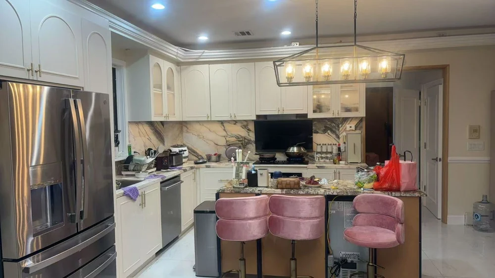 Completed New York kitchen with cream arched cabinetry, marble backsplash and a stone-topped island with bar stools