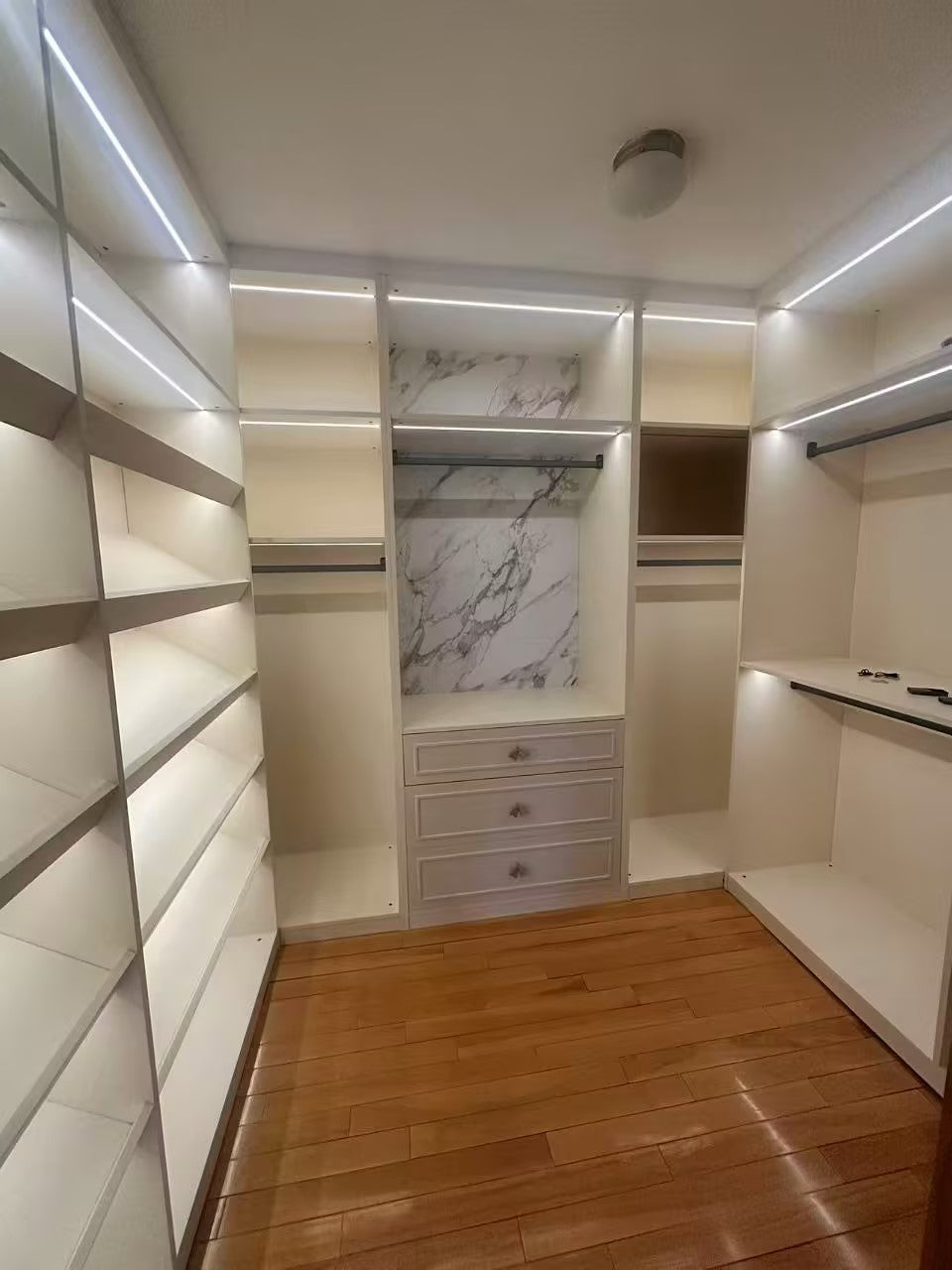 Finished small closet with shoe shelving, hanging rails and stone-grain back panel